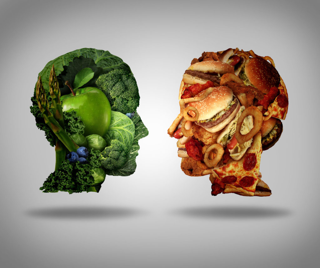 Head outline of green veggies and a head outline of junk food