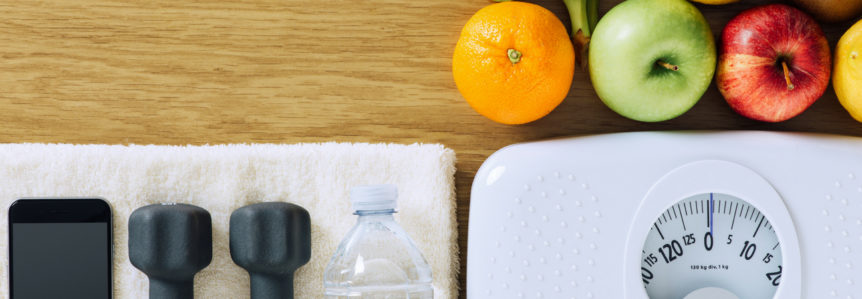 Fruits laying next to lifting weights, bottled water, and a scale.
