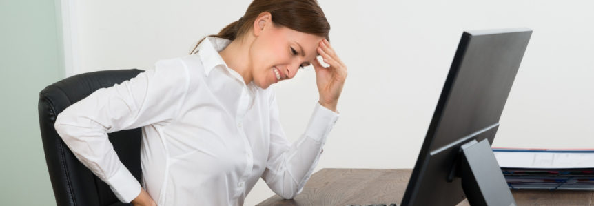 Woman sitting at a desk experiencing back pain.