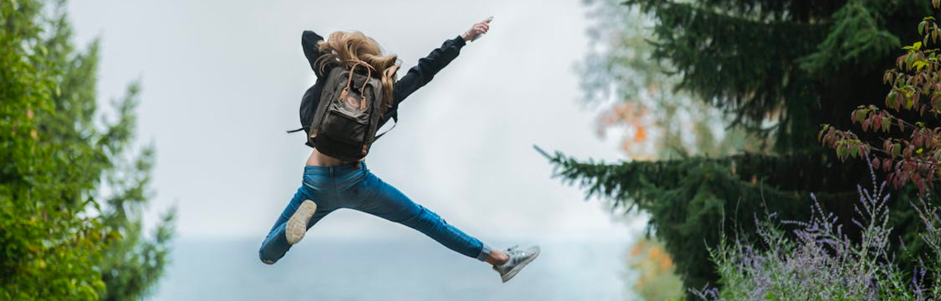woman jumping into the air with backpack